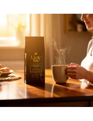 Tasse chaude fumante à côté d’un paquet noir de thé biologique “Li-Oy tea” sur une table en bois, lumière naturelle, ambiance co